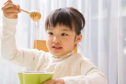 young girl holding a bowl of honey and honey holder